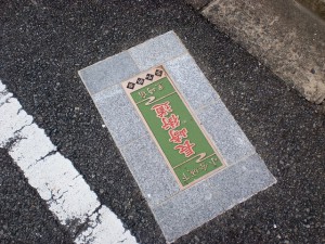 長崎街道八幡茶屋郵便局横の五差路付近に埋め込まれて長崎街道を示すプレートの画像